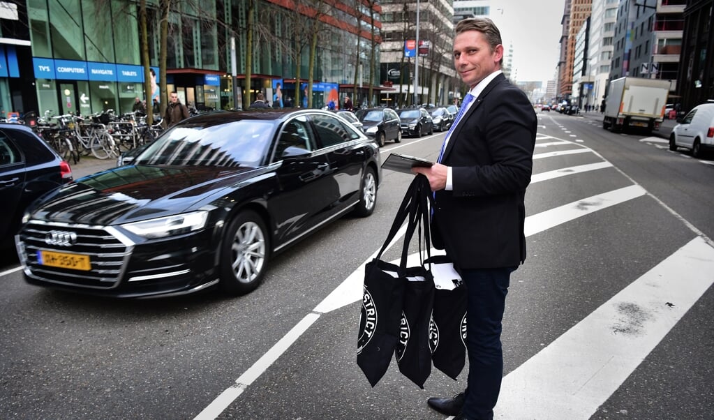 Een bezorger in pak van bezorgbedrijf Emily Company levert bestelde sneakers af bij iemand op kantoor. Ze kunnen ter plekke gepast worden en eventueel weer retour meegenomen worden. ( beeld Marcel van den Bergh)