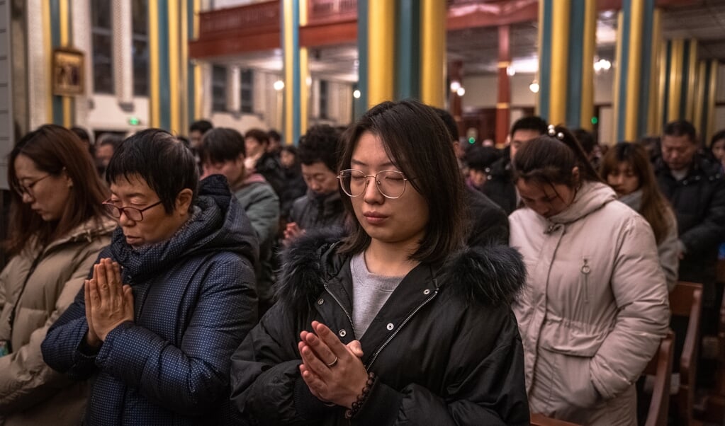 Kerkgangers tijdens de kerstnachtmis in de rooms-katholieke Xishikukerk in Beijing.  (beeld EPA/ROMAN PILIPEY)