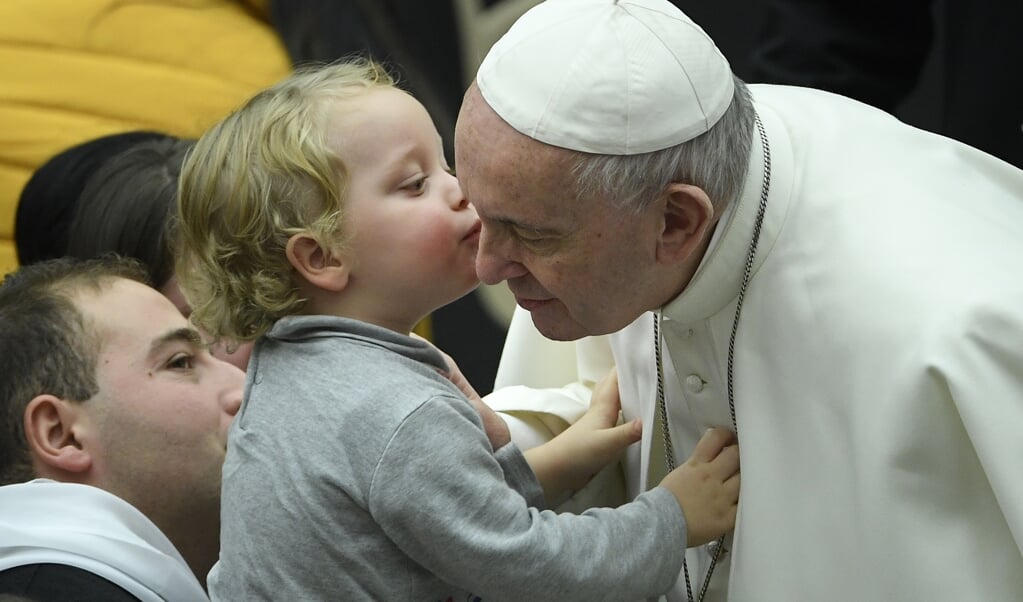 Een peuter geeft paus Franciscus een kus tijdens diens wekelijkse audiëntie in het Vaticaan. (beeld afp / Filippo Monteforte)