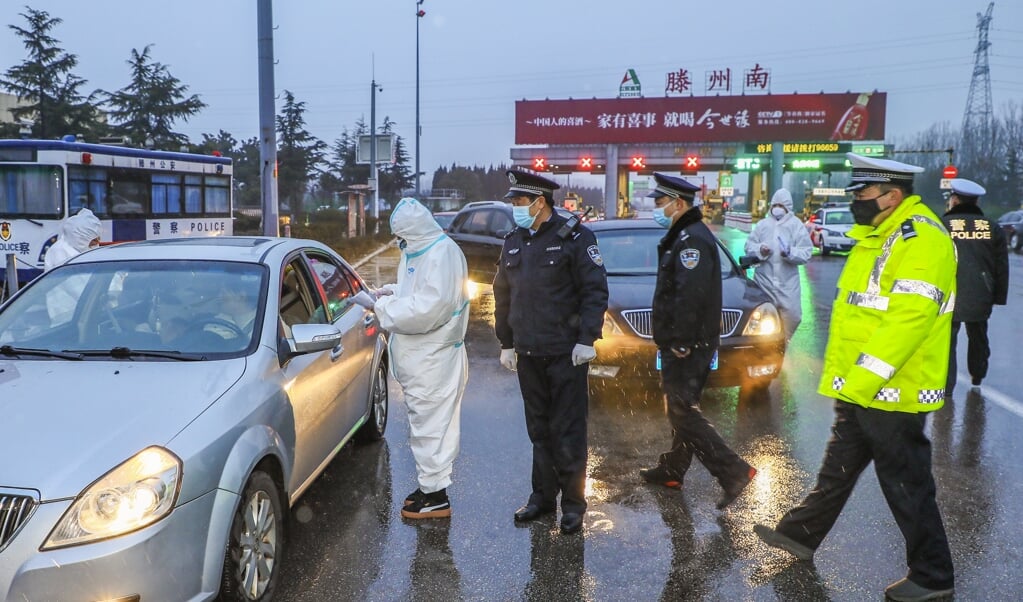 Een controlepost aan de buitenrand van Wuhan, waar de gegevens van passanten worden genoteerd. (beeld afp)