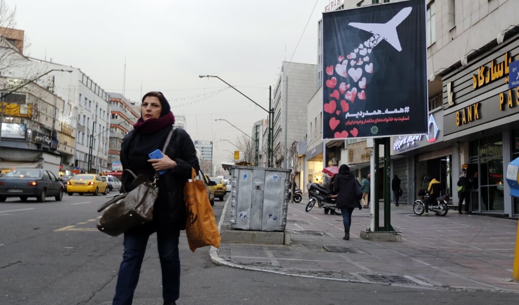 Iran probeert z’n medeleven te tonen na het neerschieten van vlucht PS572 met deze poster in de straten van Teheran: ‘We voelen allemaal pijn en we leven mee’, staat erop. ( beeld EPA/ABEDIN TAHERKENAREH)