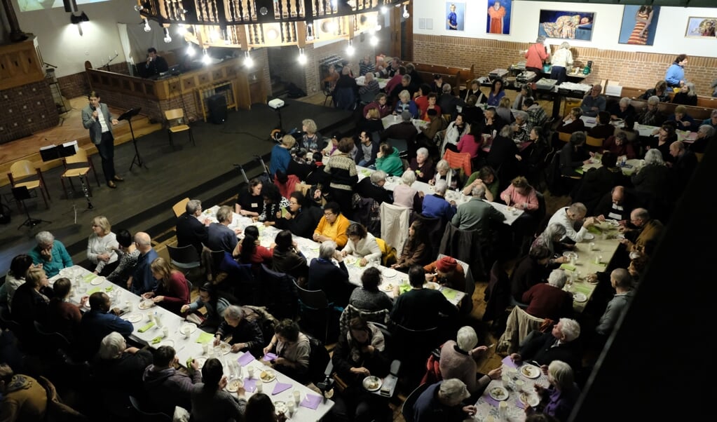 Vrolijk geroezemoes in een kerk die vol tafels staat: de nieuwjaarsmaaltijd van Kerk&Buurt in de Nassaukerk te Amsterdam. (beeld J. Dersjant )