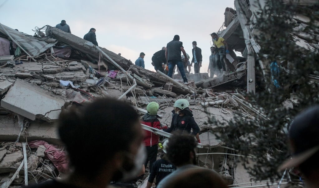 Vrijwilligers zoeken naar overlevenden onder het puin in de Turkse stad Izmir. (beeld afp / Mert Cakir)