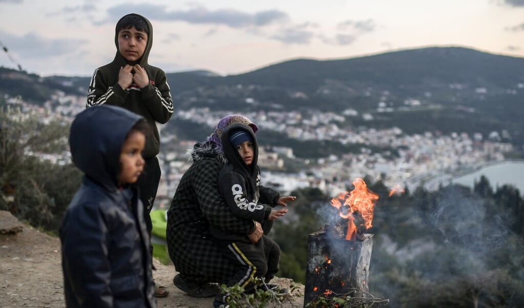 Een man steekt een vuur aan voor zijn gezin in het onofficiële kamp van het eiland Samos (beeld afp / Aris Messinis)
