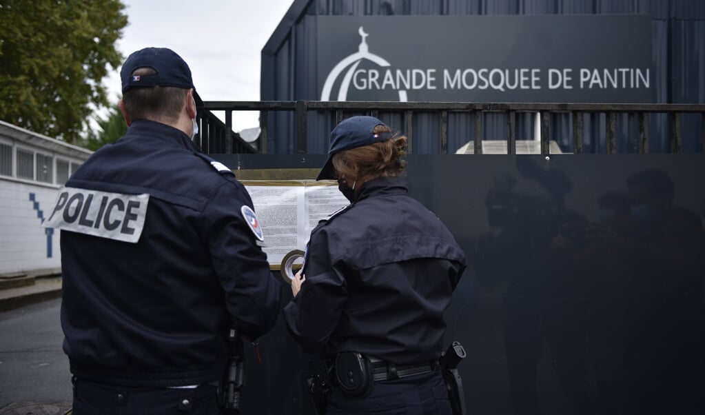 Franse agenten bevestigen een decreet aan de poort van de Grote Moskee van Pantin, waarin staat dat het gebedshuis gesloten wordt. (beeld Epa/julien de Rosa)