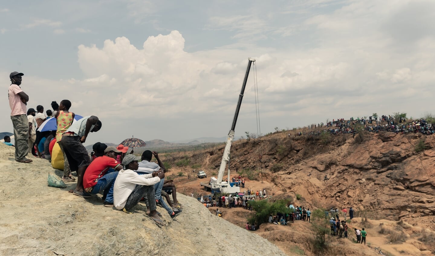Omstanders kijken naar de reddingswerkers die proberen water uit de schacht te pompen om de mijnwerkers te bereiken.