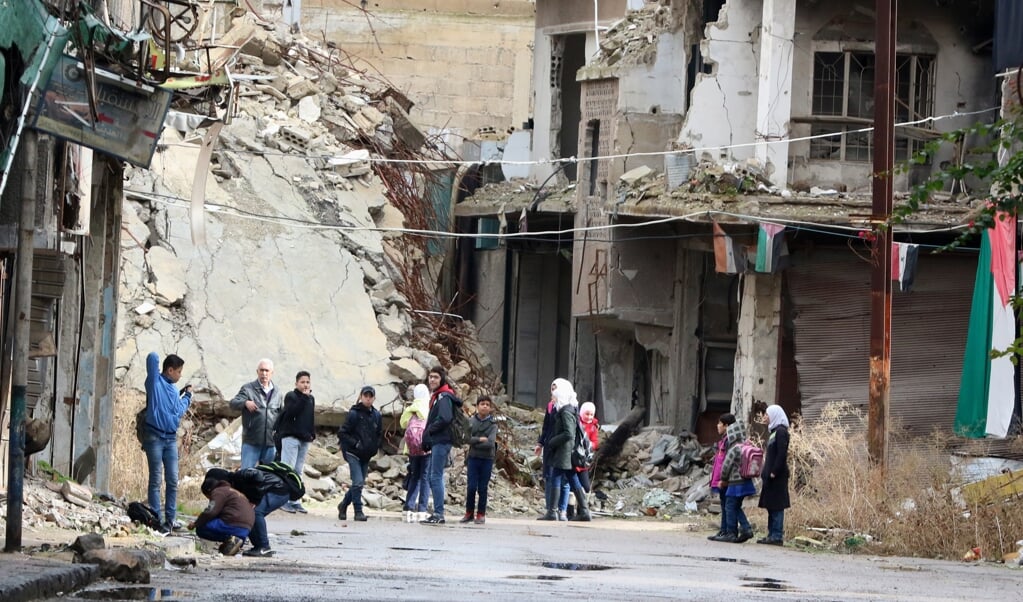 Kinderen tussen de gebouwen van het voormalige vluchtelingenkamp al Yarmouk, nabij Damascus.  (beeld epa / Youssef Badawi)
