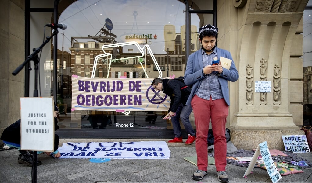 Demonstranten tijdens een actie bij de Apple Store. Volgens Extinction Rebellion draagt Apple bij aan de discriminatie van Oeigoeren, omdat het elektronicabedrijf gebruik zou maken van Oeigoerse dwangarbeiders.   (beeld anp / Koen van Weel)