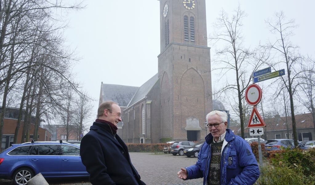 Dominee Krijn Hage (l.) in gesprek met zijn buurman. Op de achtergrond de Pieterskerk. (beeld Dick Vos)