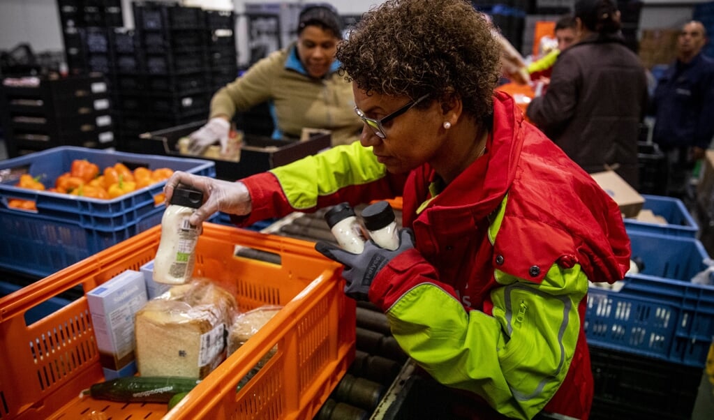 Een vrijwilliger verpakt een voedselpakket in het distributiecentrum van de Voedselbank in Rotterdam (2019). Er is op dit moment een wachtlijst bij deze voedselbank. Rotterdam voert de lijst aan van steden met relatief de meeste inwoners met een laag inkomen, meer dan tien procent.  (beeld anp / sem van der wal)