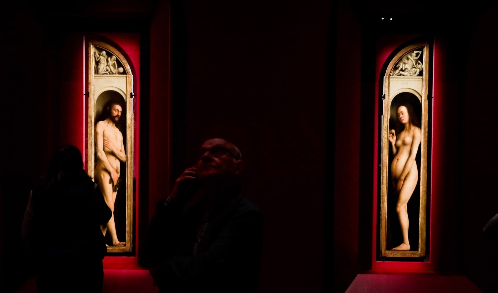 Bezoekers van de tentoonstelling Van Eyck kijken naar de panelen Adam en Eva. Hamvraag: zijn de vijgenblaadjes origineel, of preutse toevoegingen?