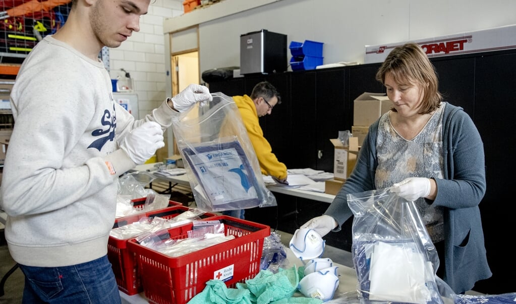 Vrijwilligers in Boskoop stellen bij het Rode Kruis pakketten beschermingsmiddelen samen voor hulpverleners. Tijdens de huidige coronacrisis zijn er tekorten aan mondkapjes en andere middelen voor persoonlijke bescherming. (beeld anp / Sem van der Wal)