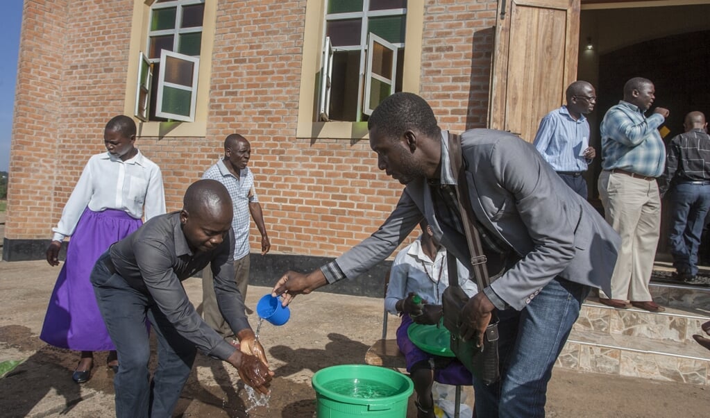 Kerkgangers in Malawi wassen bij de ingang van de kerk hun handen tegen het coronavirus. Wanneer moet je als zendingsorganisatie uit een land als Malawi je mensen terughalen? (beeld afp / Amos Gumulira)