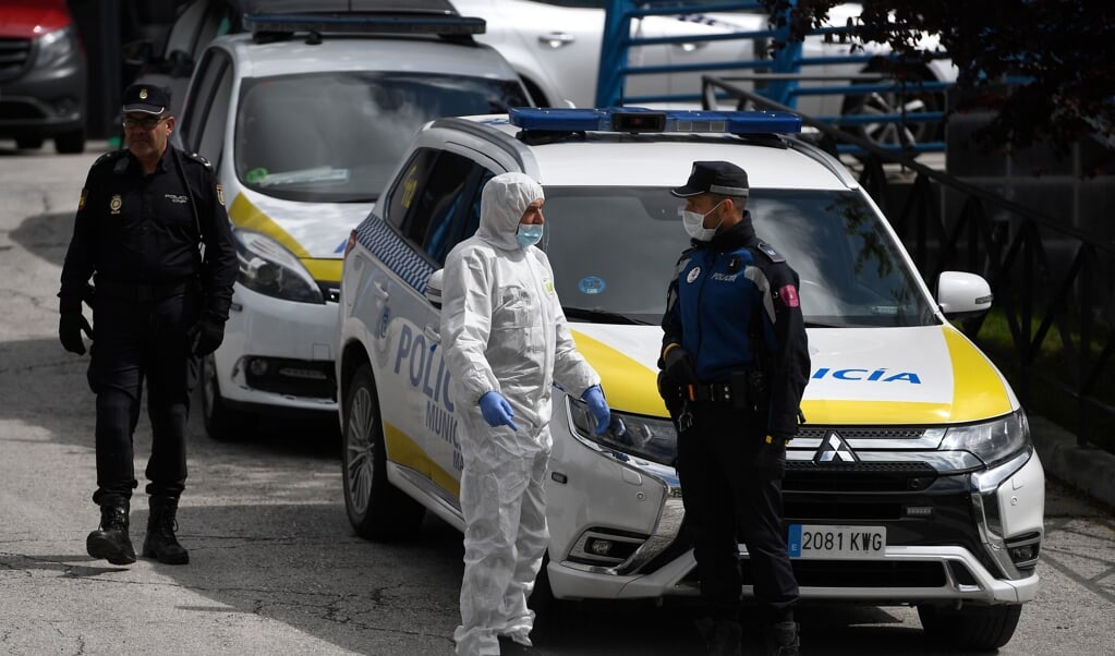 Een Spaanse politieagent is in gesprek met een medewerker van de Spaanse noodeenheid UME. Zij staan vlak bij kunstijsbaan Palacio de Hielo, dat als tijdelijk mortuarium dient. (beeld afp / Pierre-Philippe Marcou)