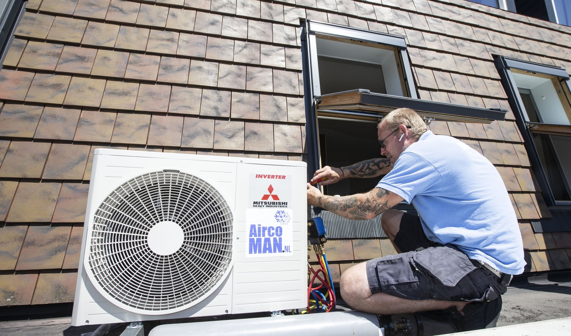 Een installateur plaats een airconditioner in een woning in Hooglanderveen. Door het warme weer gaan mensen op zoek naar verkoeling in hun huis.