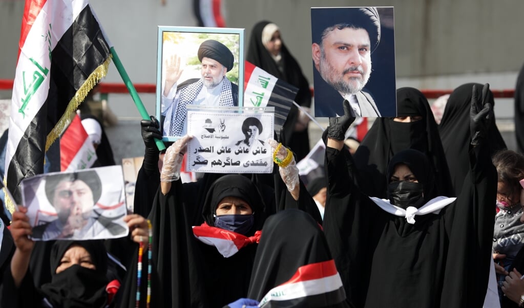 Aanhangers van de Irakese leider Muqtada al-Sadr houden op 27 november 2020 Irakese vlaggen en diens portret omhoog. Al Sadr pleitte de afgelopen weken voor politieke hervormingen en strijd tegen corruptie in het land. (beeld Epa / Ahmed Jalil)