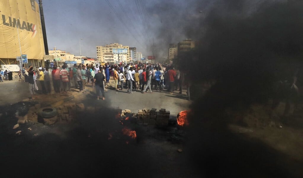 Sudanese demonstranten gooien met stenen en verbranden autobanden om in Khartoem de weg te blokkeren.  (beeld afp / Omar Al-Bashir)