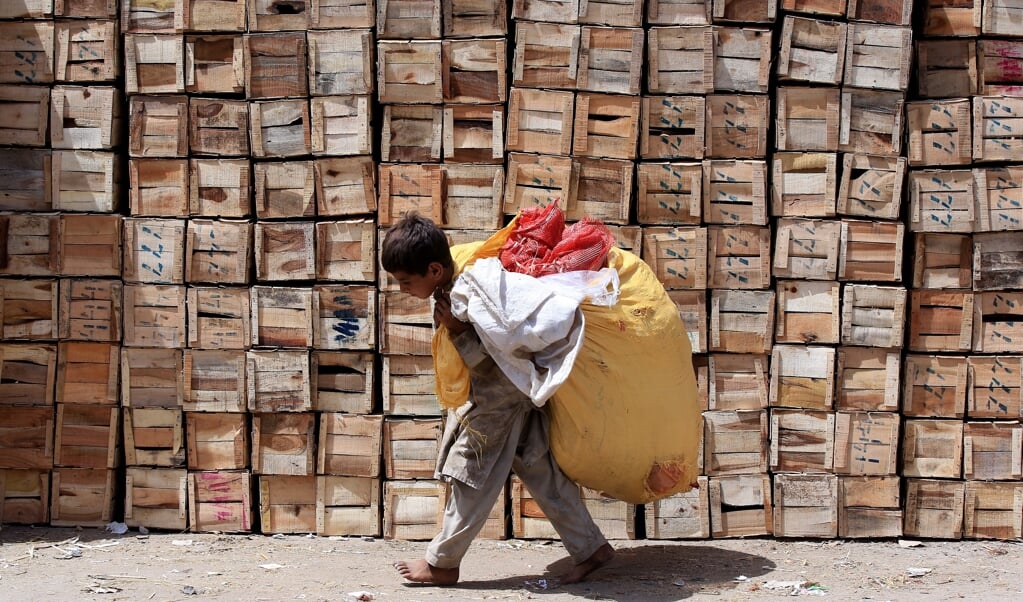 Een Pakistaanse jongen verwerkt recyclebaar afval. Wereldwijd werken 160 miljoen kinderen illegaal, ook voor Nederlandse bedrijven. (beeld epa / Bilawal Arbab)