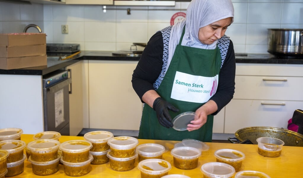 Een vrijwilliger pakt een maaltijd in die de stichting Samen Sterk Vrouwen West uitdeelt aan minderbedeelden. (beeld anp / Evert Elzinga)