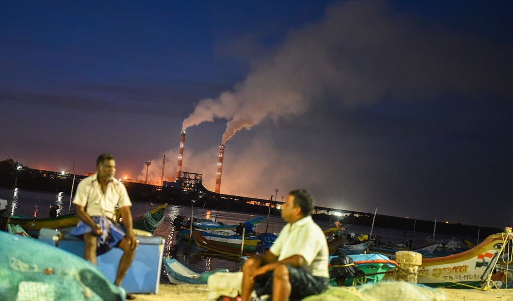 Lokale vissers zitten langs de Ennore-kreek terwijl rook uit de schoorsteen van de thermische centrale van TANGEDCO in Chennai, India komt. (beeld epa / Idrees Mohammed)