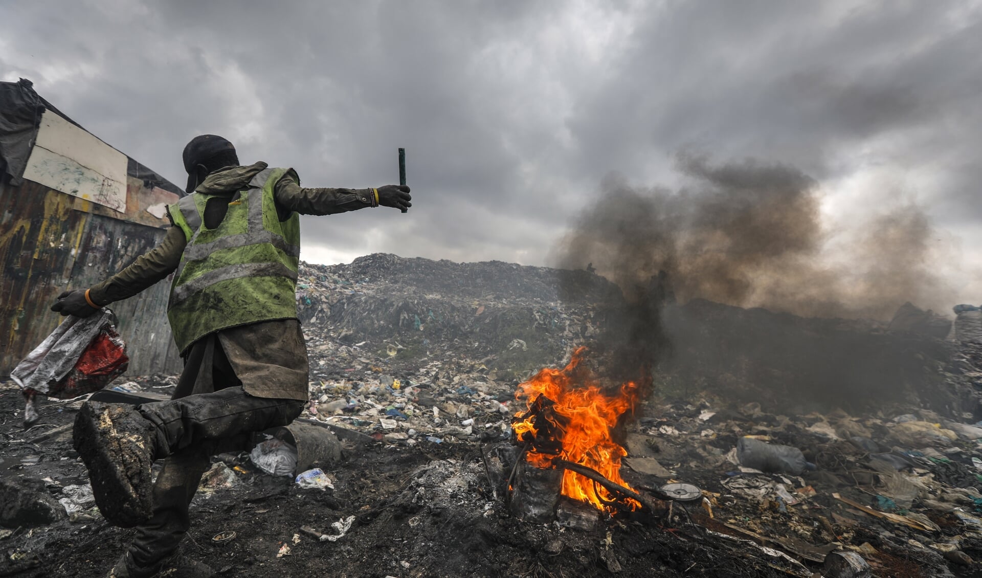 Een jongeman verbrandt een motor om koper te winnen op de Dandora-vuilnisbelt in Nairobi. 