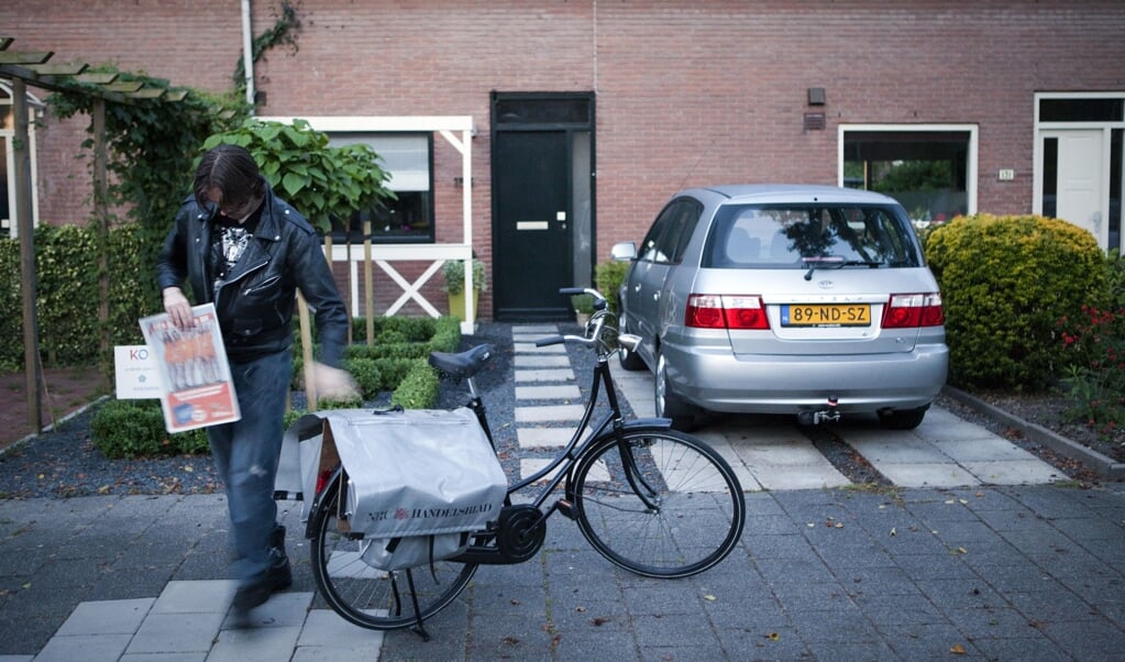 Een krantenbezorger in Hoofddorp pakt zijn fietstassen in.  (beeld anp / Nils van Houts)