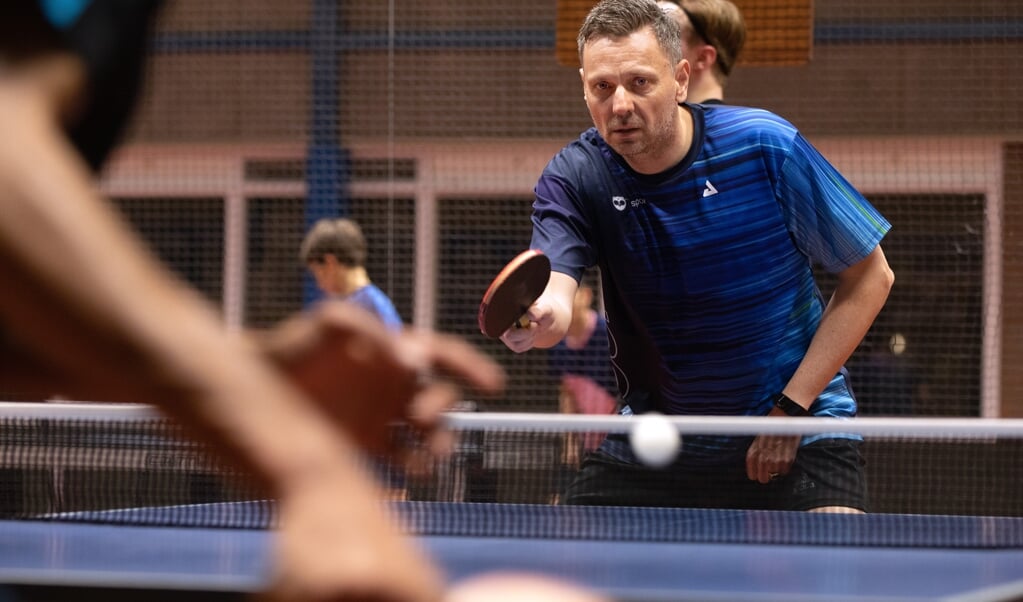 Michel de Boer werd op 51-jarige leeftijd Nederlands kampioen tafeltennis bij de heren. Op dinsdagavond traint hij de leden van zijn tafeltennisvereniging TOGB, onder wie zijn zoon. (beeld Dirk Hol)