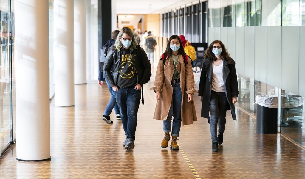 Studenten op het Science Park van de Universiteit van Amsterdam dragen, eerder deze maand, vanwege de aanscherping van coronaregels, bij verplaatsingen een mondkapje. Een coronapas is er nog niet verplicht.  (beeld anp / Jeroen Jumelet)