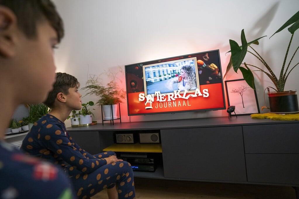 Kinderen kijken naar het Sinterklaasjournaal op televisie. De 21e editie is maandagavond van start gegaan.  (beeld anp / Jeroen Jumelet)