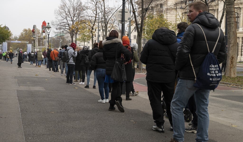 In Wenen wacht een lange rij Oostenrijkers voor een locatie waar ze een coronavaccinatie kunnen krijgen. Oostenrijk kent sinds maandag een lockdown voor niet-gevaccineerden.    (beeld afp / Joe Klamar)