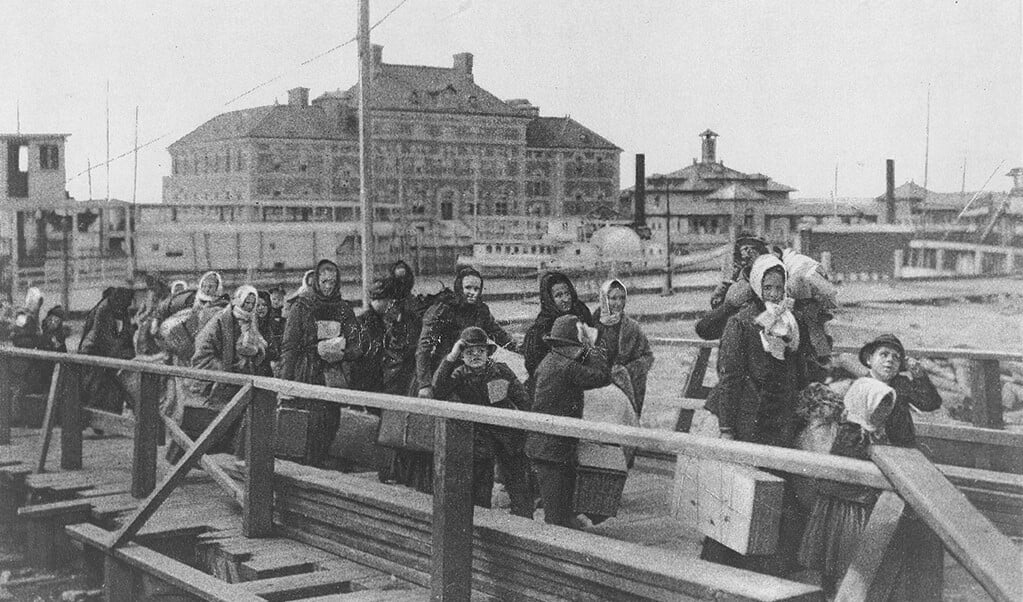 Immigranten verlaten via een loopbrug het stoomschip bij Ellis Island, 1902.  (beeld wikimedia commons)