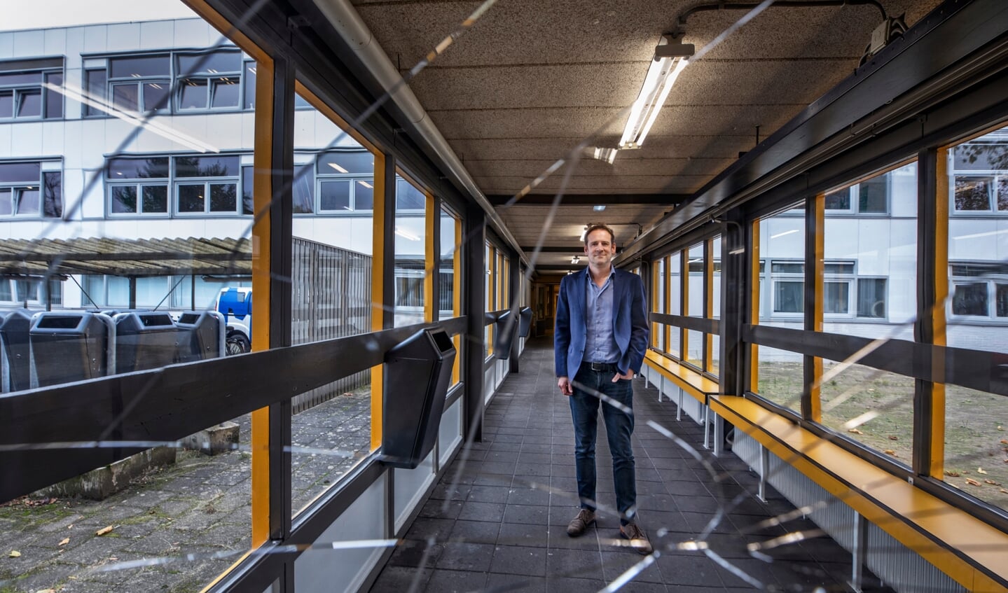 Rector Huub Nelis van school De Meergronden in Almere in een van de gangen van het verouderde gebouw met kapot glas in de deuren.