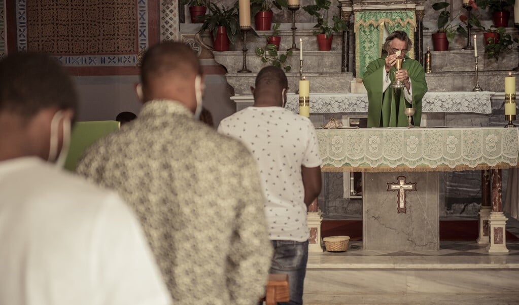 De Nederlandse priester tijdens de eucharistieviering voor vluchtelingen in de kleine rooms-katholieke kerk op het Griekse eiland Lesbos in september 2021.  (beeld Mathias Benguigui)