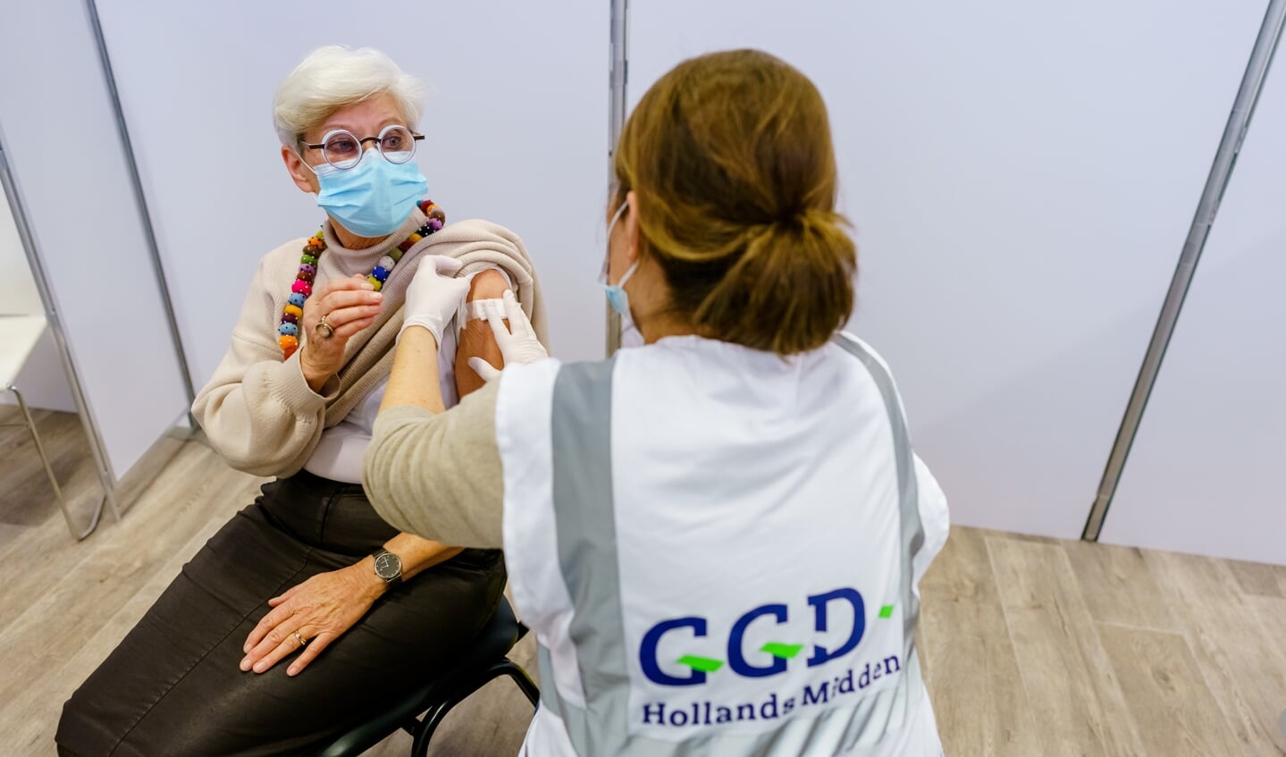Een GGD-medewerker plakt een pleister na het geven van een boosterprik in een vaccinatielocatie in Leiden.  