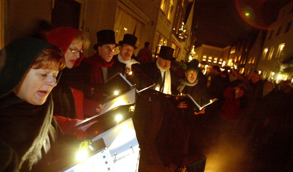 Helemaal in de sfeer: een koortje in negentiende-eeuwse kleding zingt kerstliederen op straat (toen niemand nog van een coronavirus had gehoord). (beeld anp / Ed Oudenaarden)