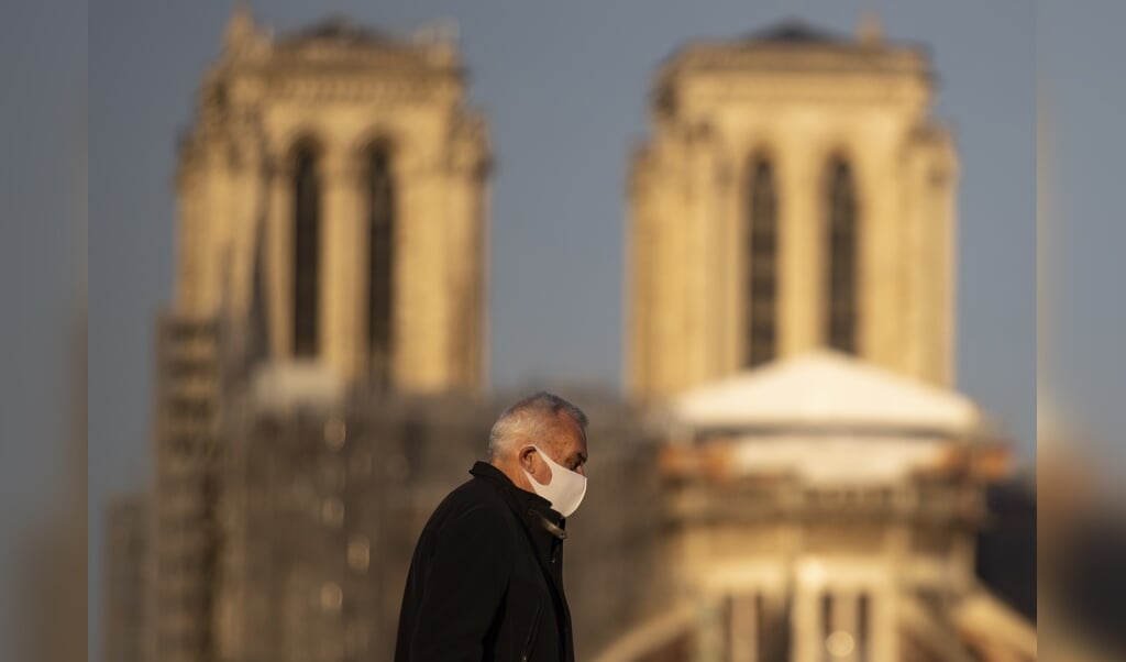 2021-12-11 09:18:53 epa09635931 A pedestrian wearing a protective face mask walks near Notre-Dame Cathedral, 11 December 2021. France is seeing new infection cases spike at nearly 57,000 every 24 hours. EPA/IAN LANGSDON (beeld Epa/ian Langsdon)