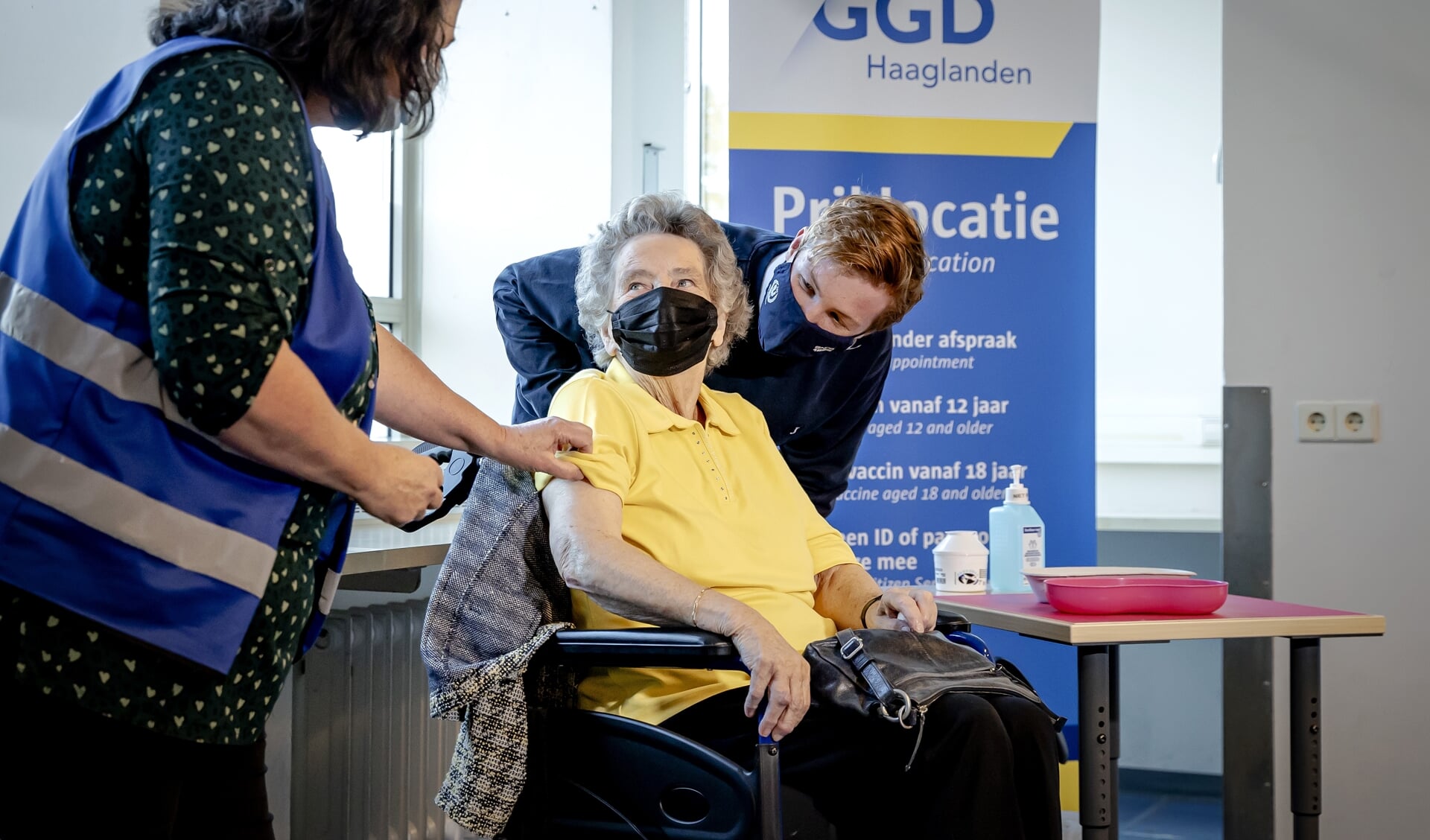 Een GGD-medewerker zet de eerste boosterprik bij een 90-jarige Haagse vrouw. Ouderen, inwoners van zorginstellingen en zorgpersoneel met direct patientencontact kunnen een boosterprik tegen het coronavirus krijgen.