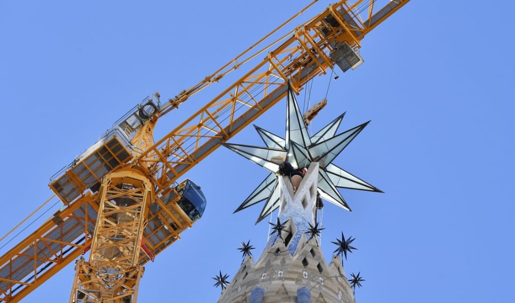 2021-11-29 10:38:15 Operators use a tower crane to install a giant star atop the Mare de Deu tower (the Virgin Tower) of the Sagrada Familia Basilica, on November 29, 2021 in Barcelona, ahead of the inauguration of the Spanish architect Antonio Gaudi's building. A 5.5 tons twelve-pointed star, was installed today at a height of 138 m atop the Sagrada Familia Basilica's Virgin Tower which will be completed on December 8, 2021, marking the Immaculate Conception Day.
Pau BARRENA / AFP  (beeld afp)