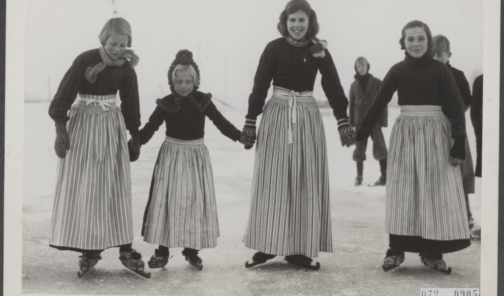 Vier Volendamse meisjes, hand in hand, op de schaats.  (beeld nationaal archief)
