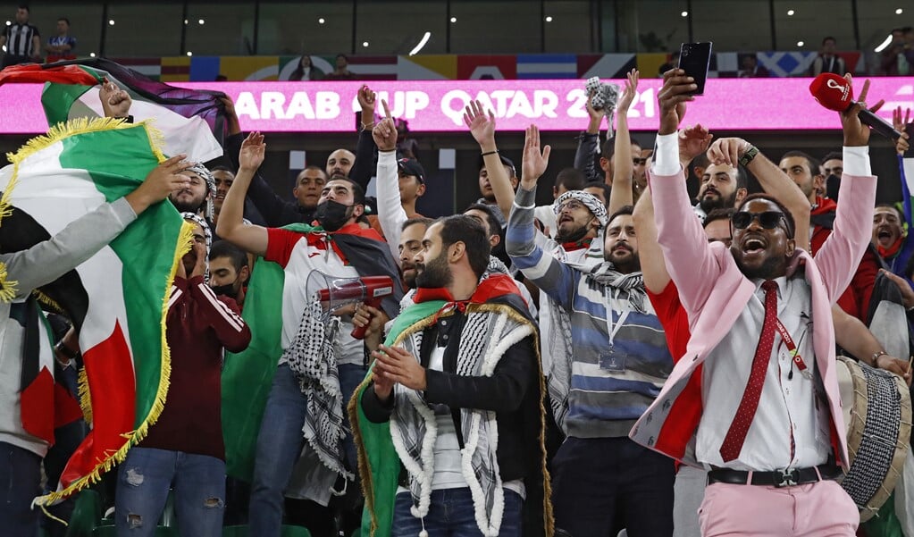 Supporters van Palestina vieren een doelpunt in het duel met Saoedi-Arabië in de Arab Cup.  (beeld afp / Jack Guez)