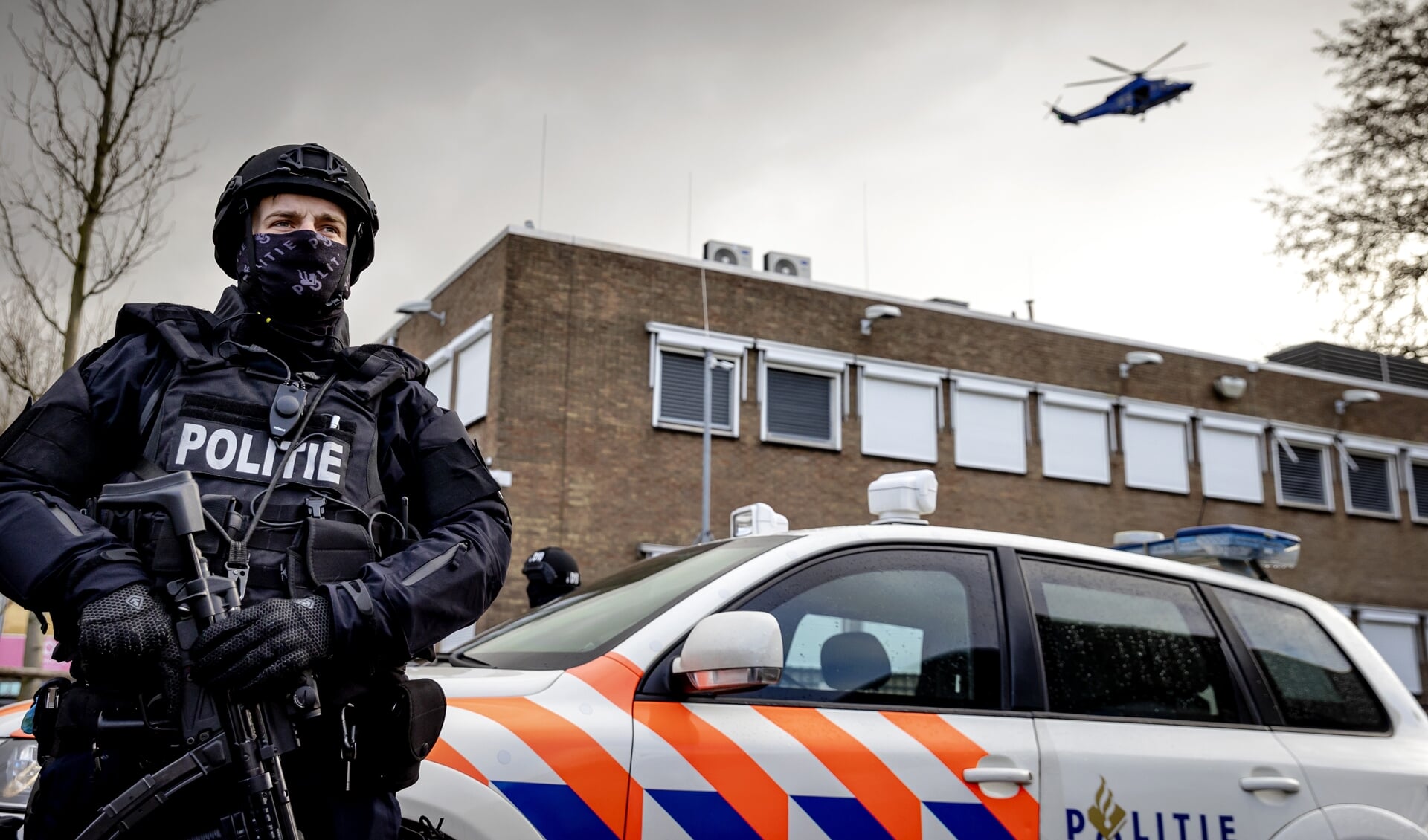 Een lid van een speciale politieeenheid houdt de wacht bij 'de bunker' in Amsterdam voor het Een lid van een speciale politieeenheid houdt de wacht bij 'de bunker' in Amsterdam voor het