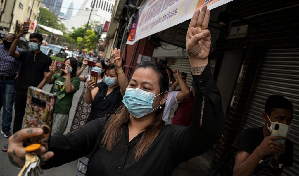 Een vrouw in Kuala Lumpur, aanhanger van de Nationale Liga voor Democratie in Myanmar, geeft een groet als statement tegen de militaire coup in Myanmar. (beeld afp / Mohd Rasfan )
