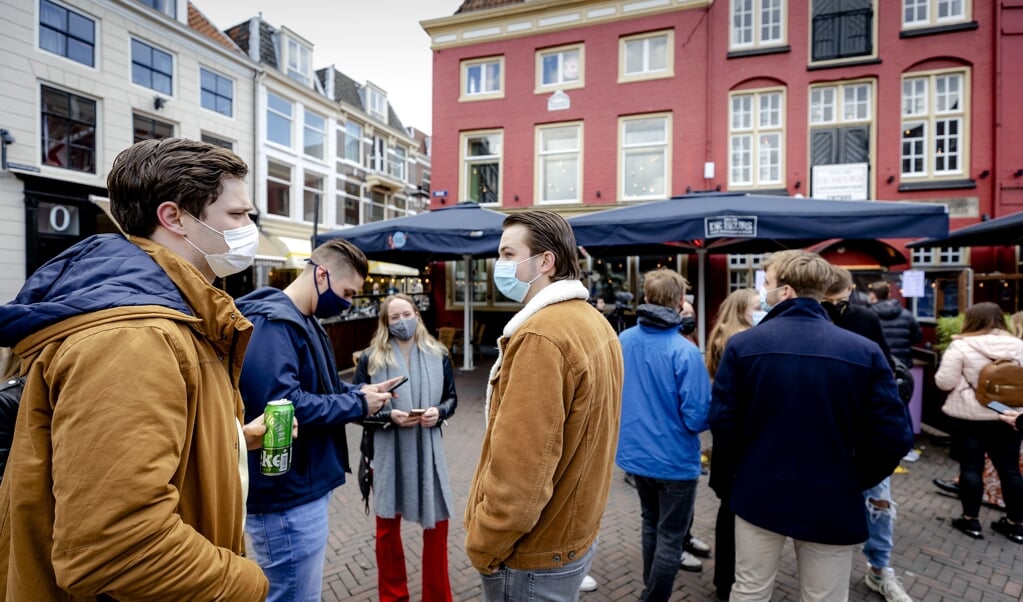 Bezoekers staan in de rij voor café De Beurs. Vijf Utrechtse cafés laten enkele dagen gasten toe, op vertoon van een negatief coronatestbewijs.  (beeld anp / Robin van Lonkhuijsen)