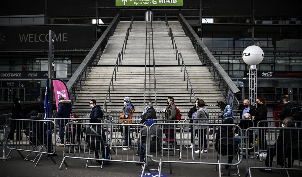 Wachten in de rij voor een prik in het Stade de France in Saint-Denis. Hoe meer mensen al zijn ingeënt, des te sterker de bereidheid toeneemt, denkt de regering. (beeld afp / Christophe Archambault)