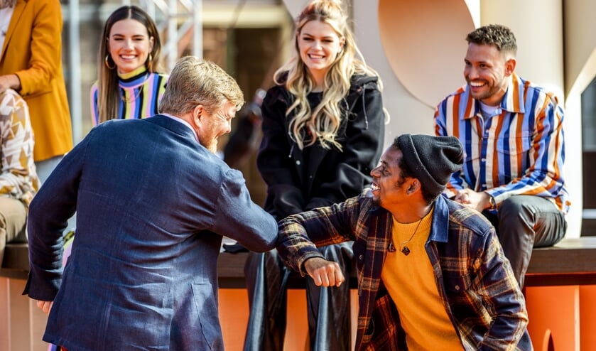 Koning Willem-Alexander geeft een elleboogje aan rapper Typhoon (rechts) tijdens de repetities van The Streamers. Vanaf het terrein van Paleis Noordeinde sloot de gelegenheidsband met een concert Koningsdag feestelijk af. (beeld anp / royal images Sem van der Wal)