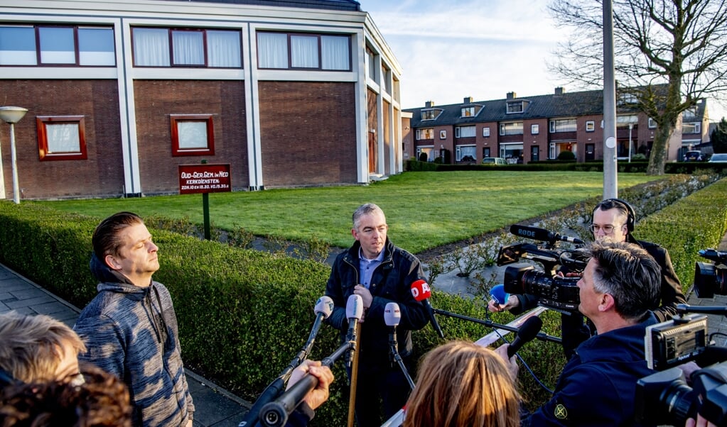 De hulpkoster en een kerkganger staan journalisten te woord bij de Mieraskerk in Krimpen aan den IJssel. (beeld anp / Robin Utrecht)