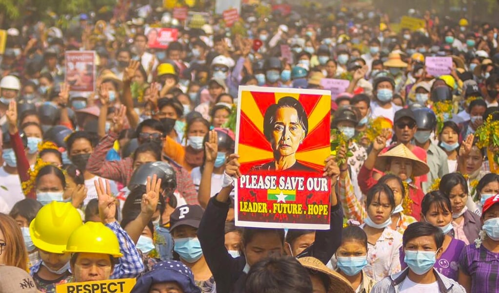 Een demonstrant houdt tijdens een protest tegen de militaire coup in Myanmar een poster met daarop een foto van Aung San Suu Kyi omhoog.   (beeld afp)