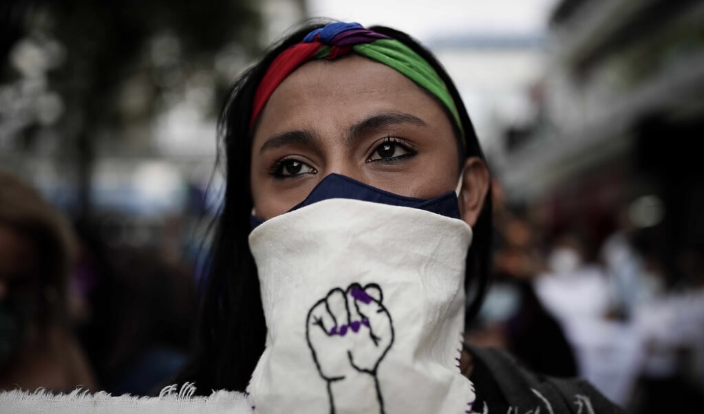 Een vrouw kijkt toe terwijl honderden vrouwen door de straten van San Jose, Costa Rica, marcheren tijdens een protest tegen vrouwenmoorden, op Internationale Vrouwendag, 8 maart 2021. (beeld epa / Jeffrey Arguedas)