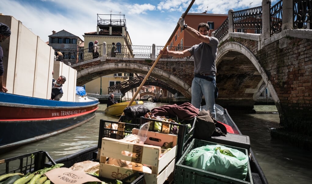 Federico Mantovan vaart, staand als een gondelier op zijn groenteboot, door de verlaten grachten van Venetië. (beeld Nicola Zolin)