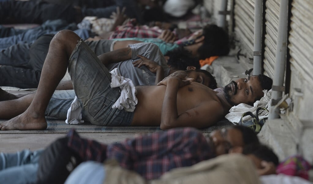 Indiase arbeiders rusten uit voor winkels in New Delhi die door de coronalockdown gesloten zijn.  (beeld afp / Arun Sankar)